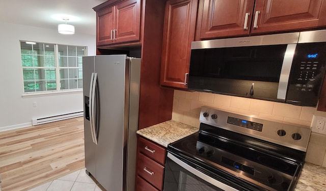 305C Torquay Court, Ridge, NY 11961 - kitchen with appliances with stainless steel finishes, a baseboard heating unit, decorative backsplash, light stone countertops, and light wood-type flooring