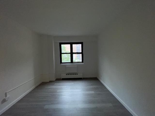 83-60 118th St Unit 3C, Kew Gardens, NY 11415 - unfurnished room with baseboard heating, wood finished floors, and baseboards