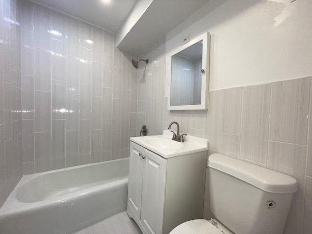 83-60 118th St Unit 3C, Kew Gardens, NY 11415 - full bath featuring toilet, vanity, bathtub / shower combination, and tile walls