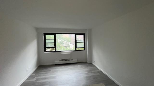 83-60 118th St Unit 3C, Kew Gardens, NY 11415 - spare room with baseboard heating, wood finished floors, and baseboards