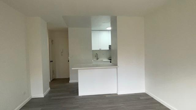 83-60 118th St Unit 3C, Kew Gardens, NY 11415 - spare room featuring dark wood-type flooring, baseboards, and a sink