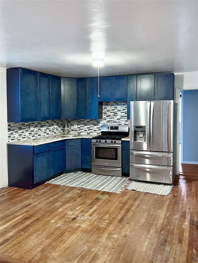 320 E 235th St, Bronx, NY 10470 - kitchen with stainless steel appliances, blue cabinets, light wood-style flooring, and tasteful backsplash