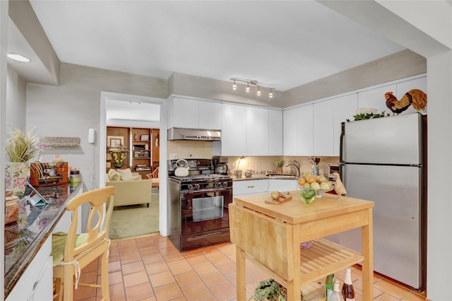 195 Loines Ave, Merrick, NY 11566 - kitchen with gas stove, freestanding refrigerator, under cabinet range hood, light tile patterned floors, and white cabinetry