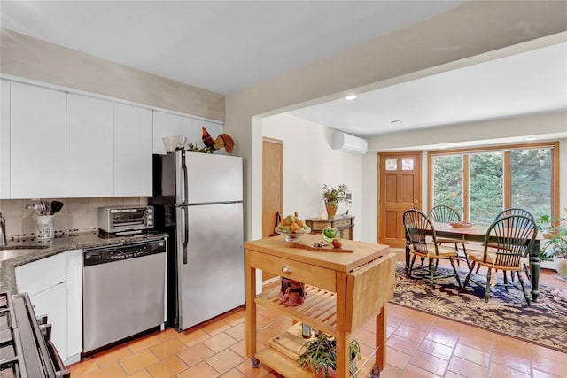 195 Loines Ave, Merrick, NY 11566 - kitchen featuring appliances with stainless steel finishes, a wall mounted air conditioner, white cabinets, dark stone countertops, and recessed lighting