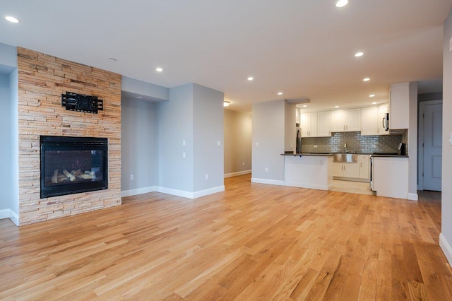 661 W Broadway Unit 204, Long Beach, NY 11561 - unfurnished living room featuring light wood-style flooring, recessed lighting, a fireplace, and baseboards