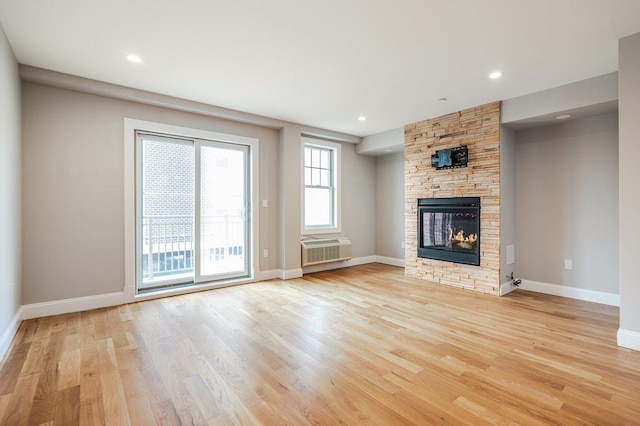 661 W Broadway Unit 204, Long Beach, NY 11561 - unfurnished living room with light wood-style floors, a wall mounted air conditioner, a stone fireplace, baseboards, and recessed lighting