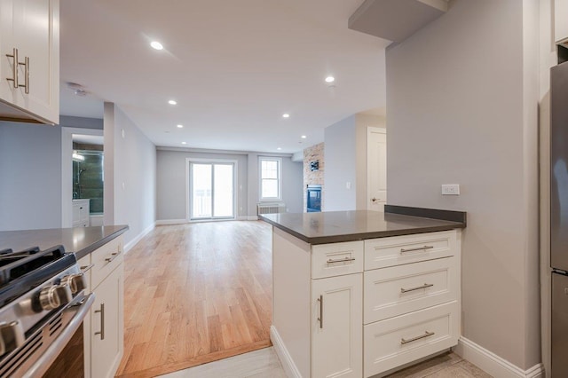 661 W Broadway Unit 204, Long Beach, NY 11561 - kitchen featuring dark countertops, stainless steel range with gas cooktop, baseboards, white cabinetry, and recessed lighting
