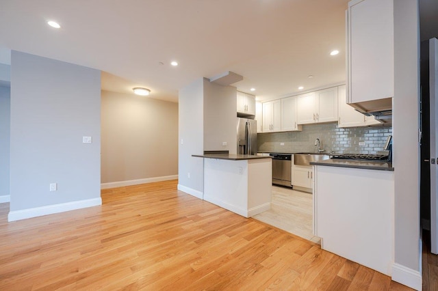 661 W Broadway Unit 204, Long Beach, NY 11561 - kitchen with appliances with stainless steel finishes, dark countertops, a sink, white cabinetry, and decorative backsplash