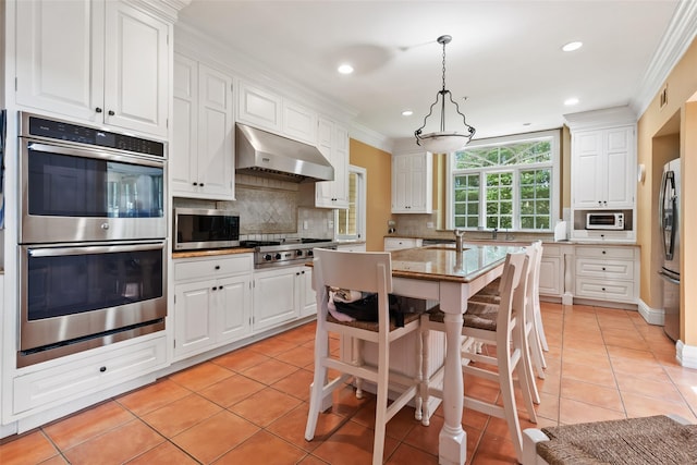 61 Carolyn Pl, Chappaqua, NY 10514 - kitchen with stainless steel appliances, under cabinet range hood, light tile patterned flooring, ornamental molding, and tasteful backsplash