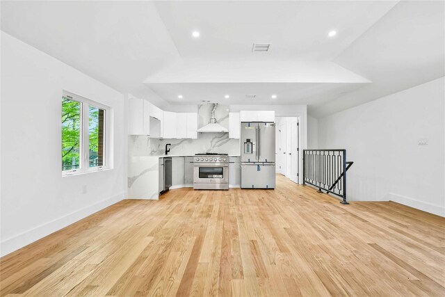 76-17 162nd St, Fresh Meadows, NY 11366 - kitchen featuring high quality appliances, wall chimney exhaust hood, light countertops, white cabinetry, and light wood finished floors