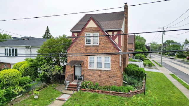 165 Page Rd, Valley Stream, NY 11581 - tudor-style house with brick siding, a front lawn, and a chimney