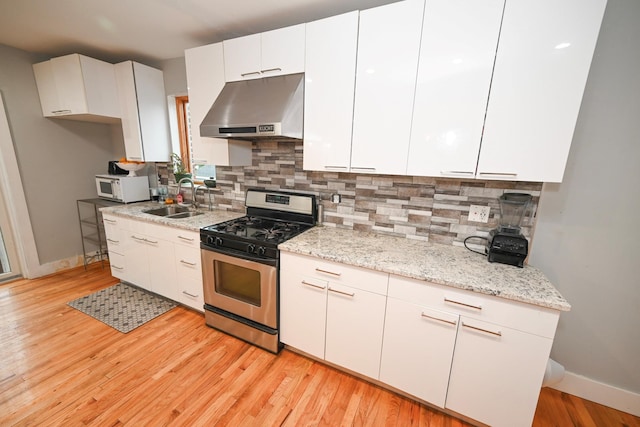 165 Page Rd, Valley Stream, NY 11581 - kitchen featuring exhaust hood, stainless steel gas stove, white microwave, a sink, and baseboards