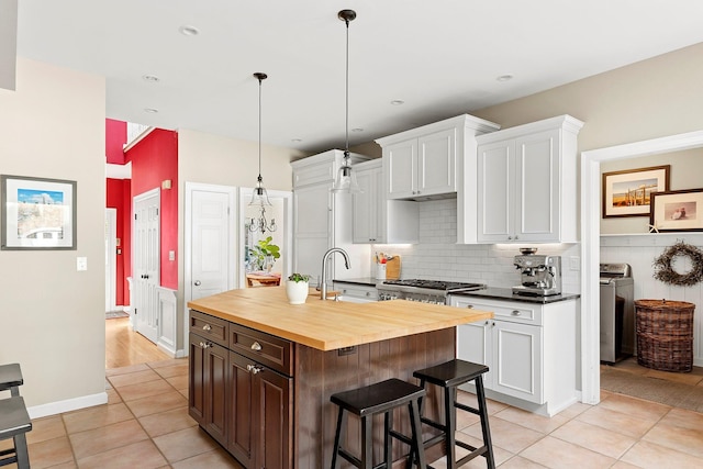 38 Maple Ave, Northport, NY 11768 - kitchen featuring wooden counters, washing machine and dryer, a sink, light tile patterned floors, and white cabinets