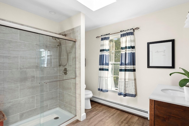 38 Maple Ave, Northport, NY 11768 - full bathroom with baseboard heating, toilet, a stall shower, vanity, and wood finished floors