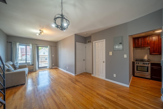 17524 89th Ave Unit C, Jamaica, NY 11432 - unfurnished living room featuring electric panel, baseboards, light wood finished floors, and a chandelier