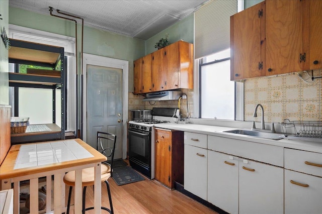 243 E 234th St, Bronx, NY 10470 - kitchen featuring black range with gas stovetop, light wood finished floors, a sink, light countertops, and an ornate ceiling