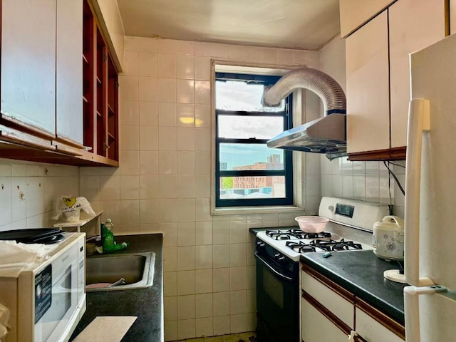 38-15 149th St Unit 6S, Flushing, NY 11354 - kitchen with gas stove, freestanding refrigerator, tile walls, white microwave, and dark countertops