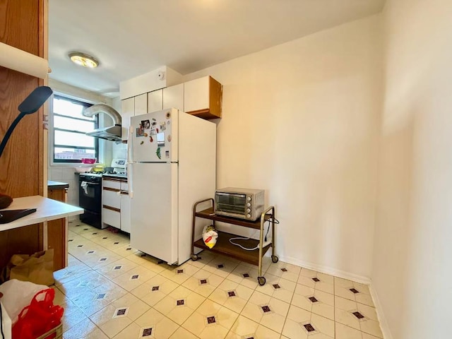 38-15 149th St Unit 6S, Flushing, NY 11354 - kitchen with freestanding refrigerator, range with gas stovetop, light tile patterned floors, wall chimney exhaust hood, and light countertops