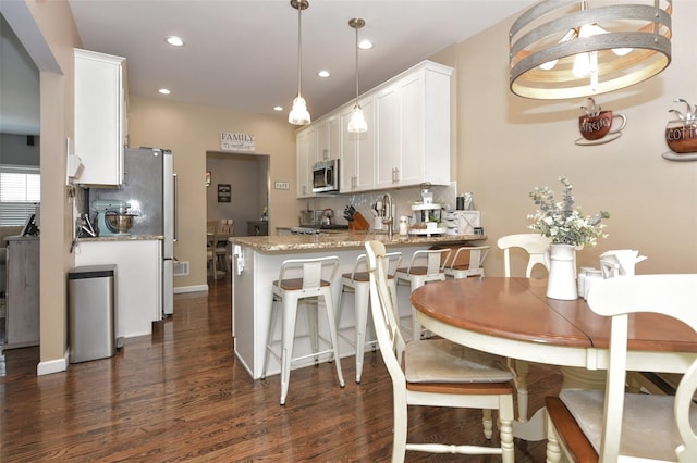 2 Hidden Creek Blvd, Monroe, NY 10950 - kitchen featuring stainless steel microwave, white cabinets, dark wood finished floors, light stone counters, and a peninsula