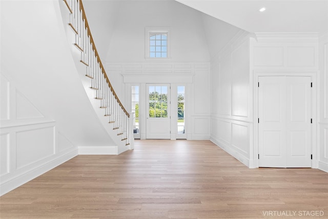 44 Club Ln, Remsenburg, NY 11960 - foyer featuring a decorative wall, high vaulted ceiling, stairs, and light wood-style floors