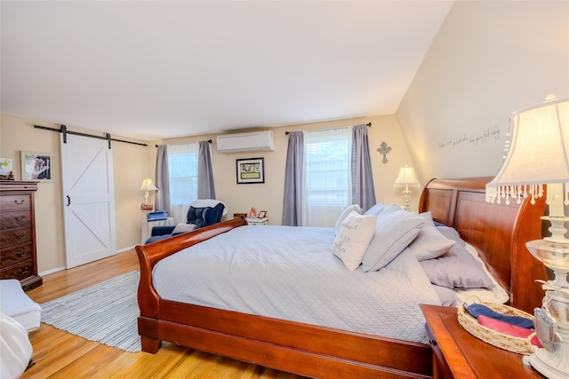58 Hooper St, Port Jefferson Station, NY 11776 - bedroom featuring a wall mounted AC, a barn door, multiple windows, and wood finished floors