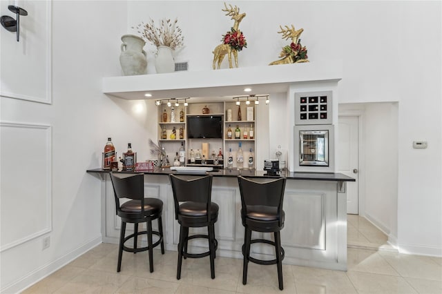 2854 Whaleneck Dr, Merrick, NY 11566 - indoor wet bar featuring a towering ceiling, baseboards, and light tile patterned flooring