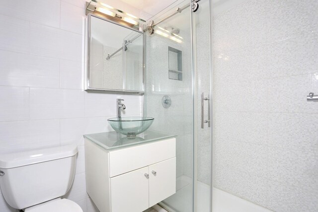 311 71st St E Unit 10A, New York Manhattan, NY 10021 - bathroom with vanity, a stall shower, and tile walls