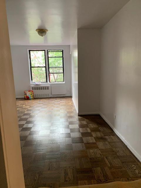 92-29 Lamont Ave Unit 2C, Elmhurst, NY 11373 - spare room featuring radiator heating unit and dark flooring