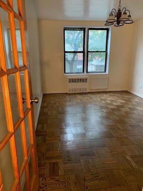 92-29 Lamont Ave Unit 2C, Elmhurst, NY 11373 - empty room featuring radiator heating unit and a chandelier