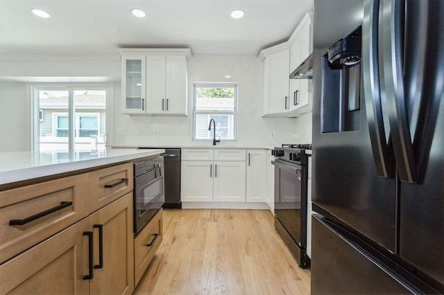 1541 Midian St, North Merrick, NY 11566 - kitchen with black appliances, light wood-type flooring, recessed lighting, glass insert cabinets, and light countertops