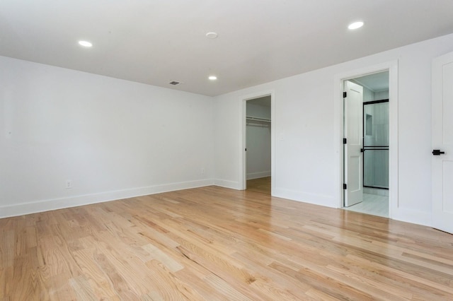 1541 Midian St, North Merrick, NY 11566 - unfurnished bedroom with light wood-style flooring, recessed lighting, baseboards, a walk in closet, and connected bathroom
