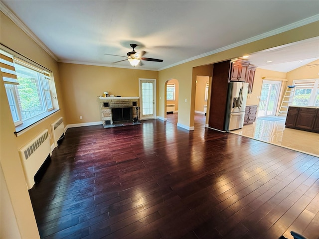 56 Elwood Rd, Northport, NY 11768 - unfurnished living room featuring radiator heating unit, a ceiling fan, hardwood / wood-style flooring, a fireplace, and crown molding