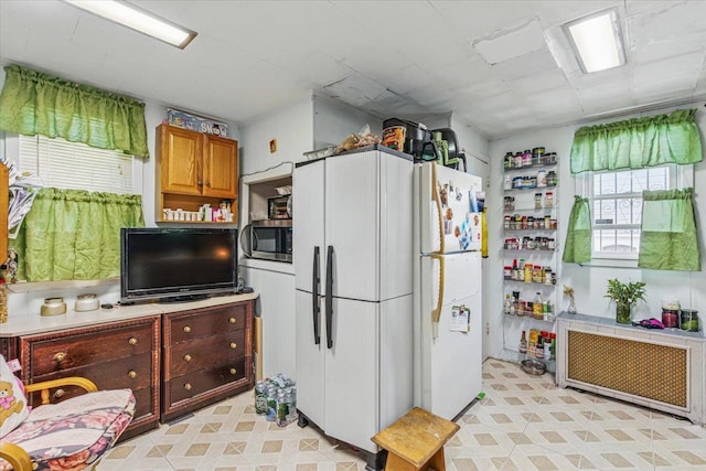 111-38 114th St, South Ozone Park, NY 11420 - kitchen featuring stainless steel microwave, radiator, freestanding refrigerator, and brown cabinets
