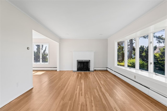 167 Secatogue Ln W, West Islip, NY 11795 - unfurnished living room with a baseboard heating unit, a baseboard radiator, light wood-style flooring, a brick fireplace, and crown molding