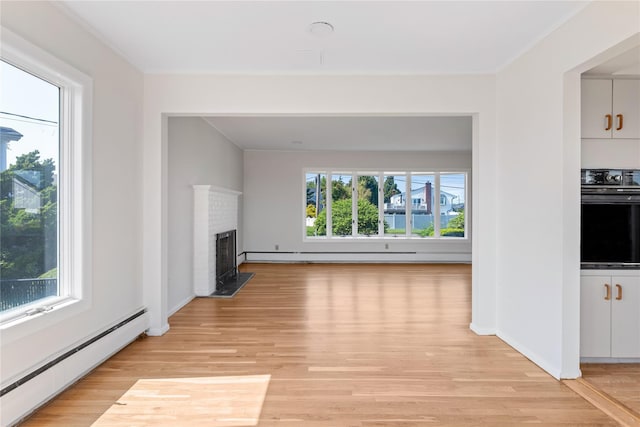 167 Secatogue Ln W, West Islip, NY 11795 - unfurnished living room featuring baseboard heating, light wood-style floors, ornamental molding, a brick fireplace, and baseboards