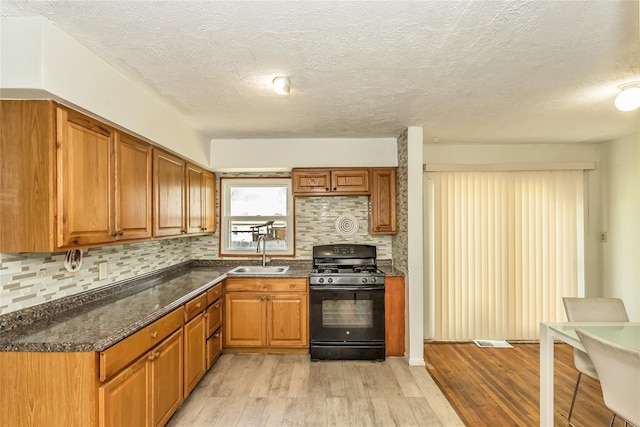 18 Hilliard Ave, Central Islip, NY 11722 - kitchen with black range with gas cooktop, a sink, light wood-style floors, a textured ceiling, and decorative backsplash