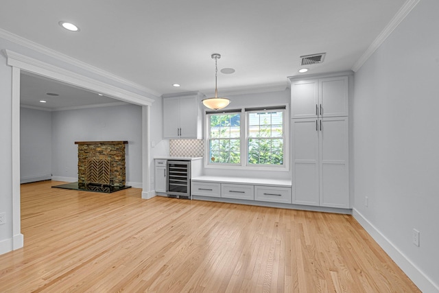 56 Washington Ave, Garden City, NY 11530 - unfurnished living room with wine cooler, light wood-type flooring, crown molding, a baseboard heating unit, and baseboards