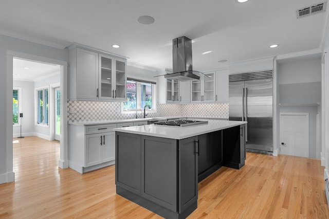 56 Washington Ave, Garden City, NY 11530 - kitchen with stainless steel appliances, island range hood, light countertops, light wood-style flooring, and ornamental molding