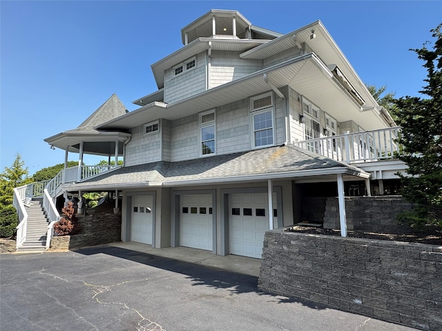 20 Frost Valley Rd, Mount Sinai, NY 11766 - view of front facade with an attached garage, a balcony, asphalt driveway, a shingled roof, and stairs