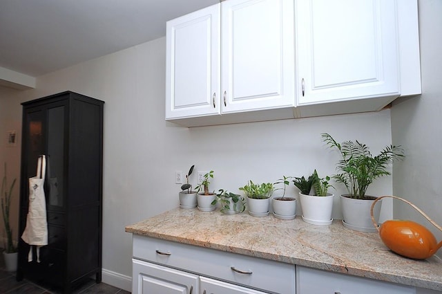 142 Garth Rd Unit 1A, Scarsdale, NY 10583 - kitchen with white cabinets, baseboards, and light stone counters