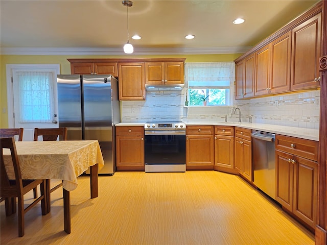 kitchen featuring stainless steel appliances, light wood-style flooring, ornamental molding, under cabinet range hood, and a sink