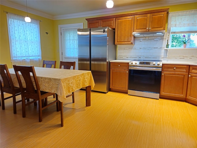kitchen featuring appliances with stainless steel finishes, under cabinet range hood, light countertops, plenty of natural light, and crown molding