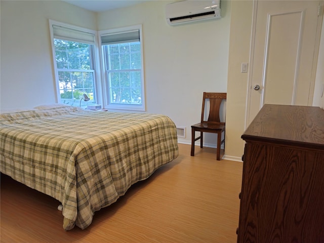 bedroom featuring a wall mounted AC, wood finished floors, and baseboards