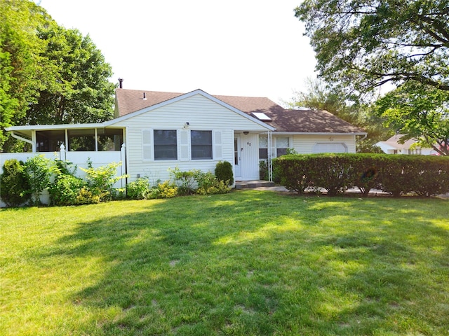 view of front of house with an attached garage, a front yard, a chimney, and a sunroom