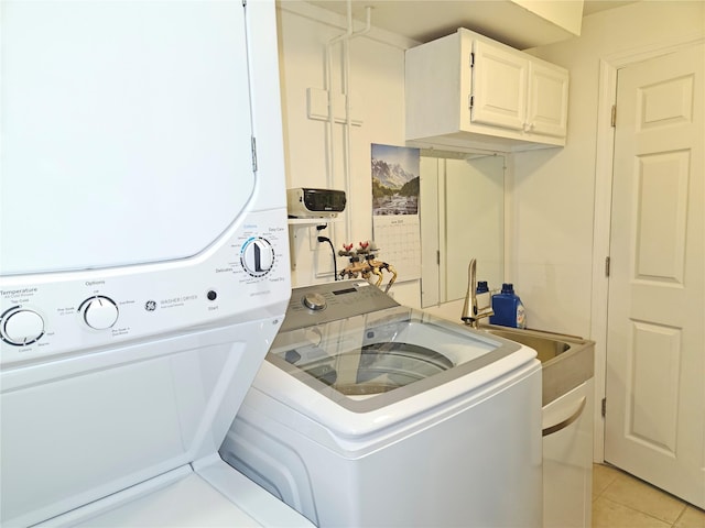 laundry room with stacked washing machine and dryer, cabinet space, and light tile patterned floors