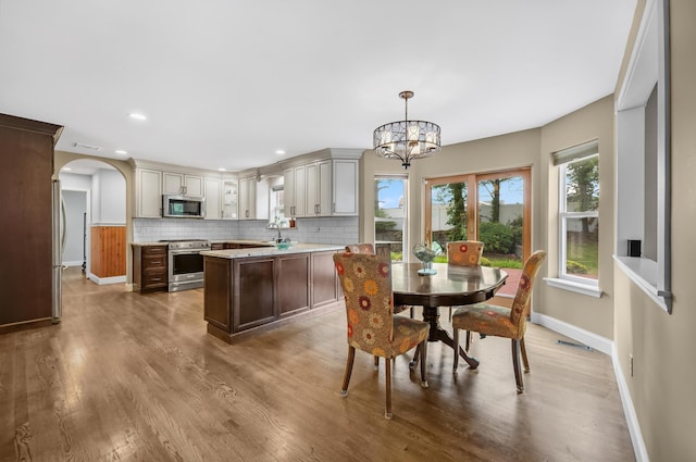 8 Tecumseh Ct, Commack, NY 11725 - dining area featuring a chandelier, baseboards, arched walkways, wood finished floors, and recessed lighting