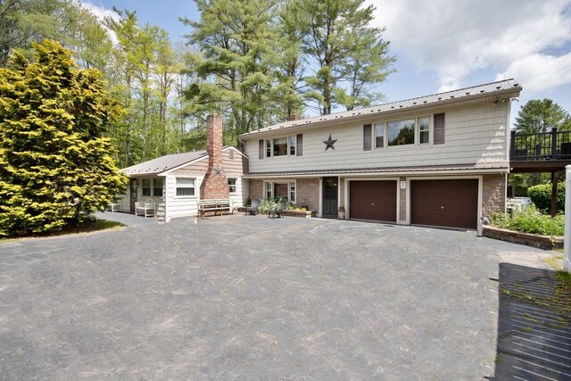 3060 State Route 17b, Cochecton, NY 12726 - view of front of property with a garage, a chimney, driveway, metal roof, and stone siding