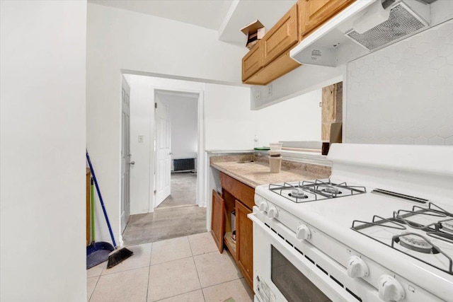 17 Lamartine Ave, Yonkers, NY 10701 - kitchen with white range with gas cooktop, premium range hood, light countertops, light tile patterned flooring, and brown cabinetry