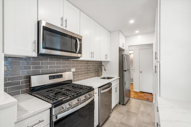 151-15 84th St Unit 1F, Howard Beach, NY 11414 - kitchen featuring appliances with stainless steel finishes, a sink, tasteful backsplash, white cabinets, and light stone counters