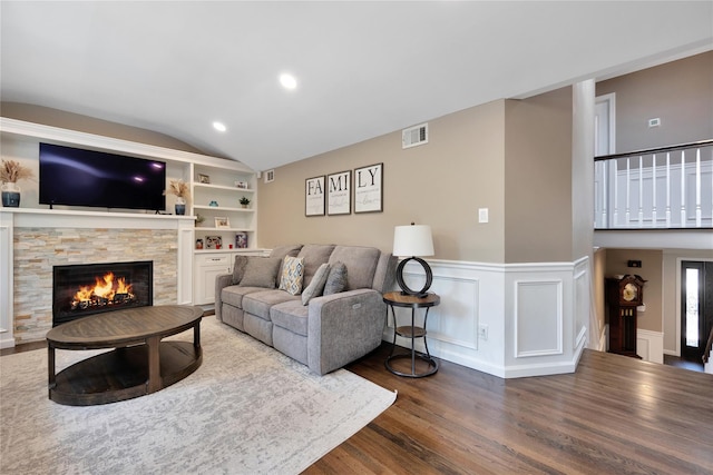 2985 Cheryl Rd, Merrick, NY 11566 - living area featuring vaulted ceiling, wood finished floors, a stone fireplace, wainscoting, and built in shelves